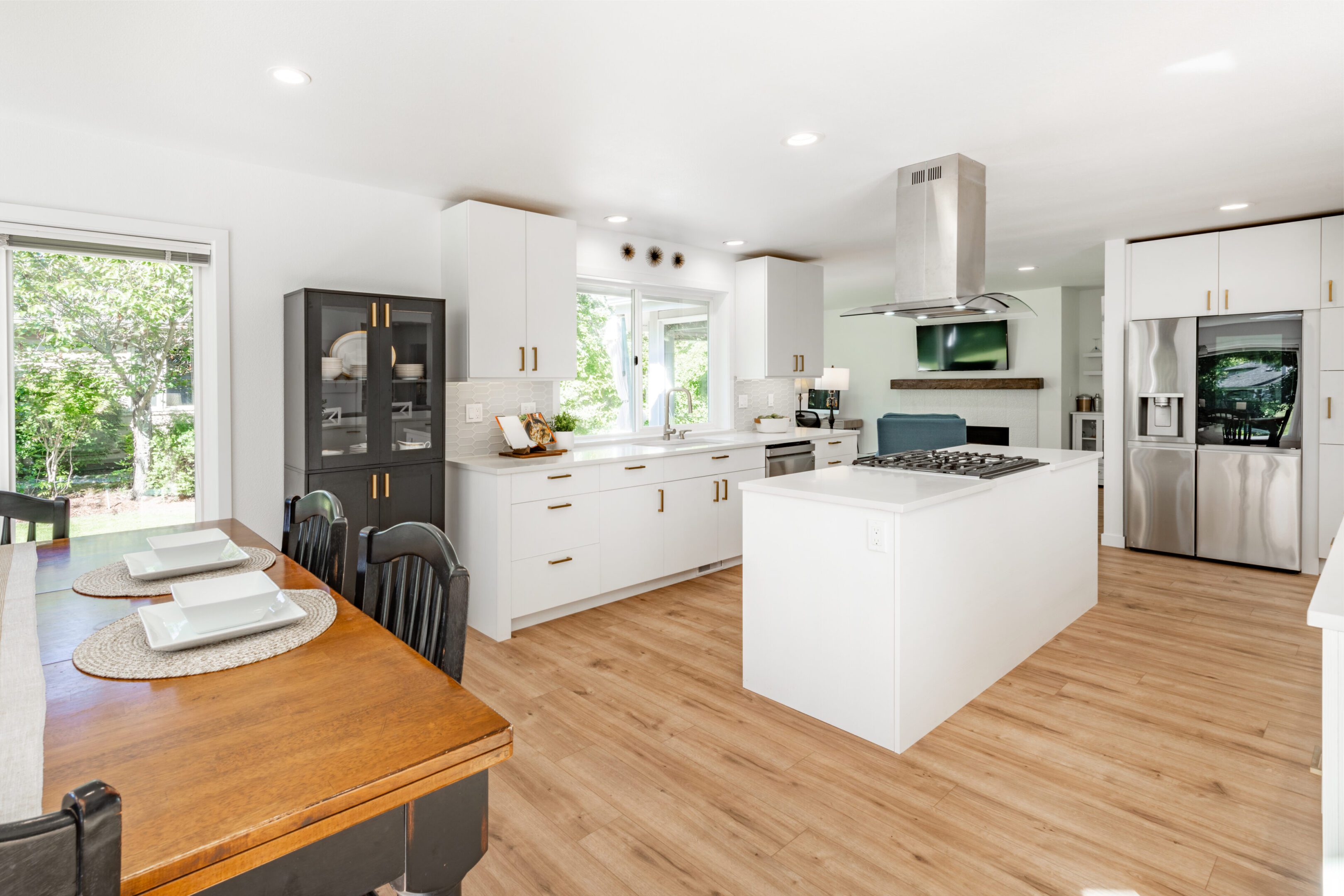 A kitchen with white cabinets and wood floors.