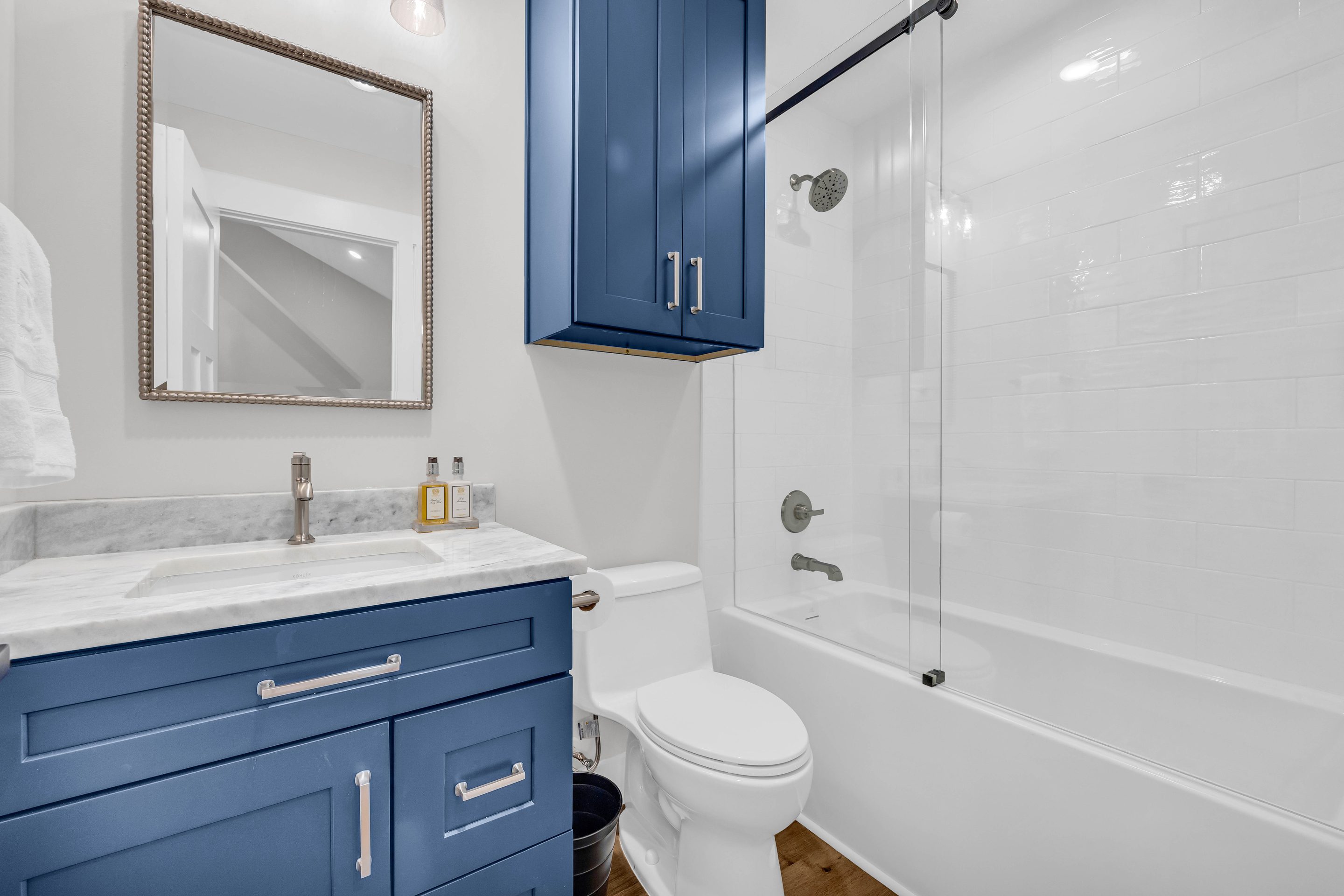 A bathroom with blue cabinets and white fixtures.