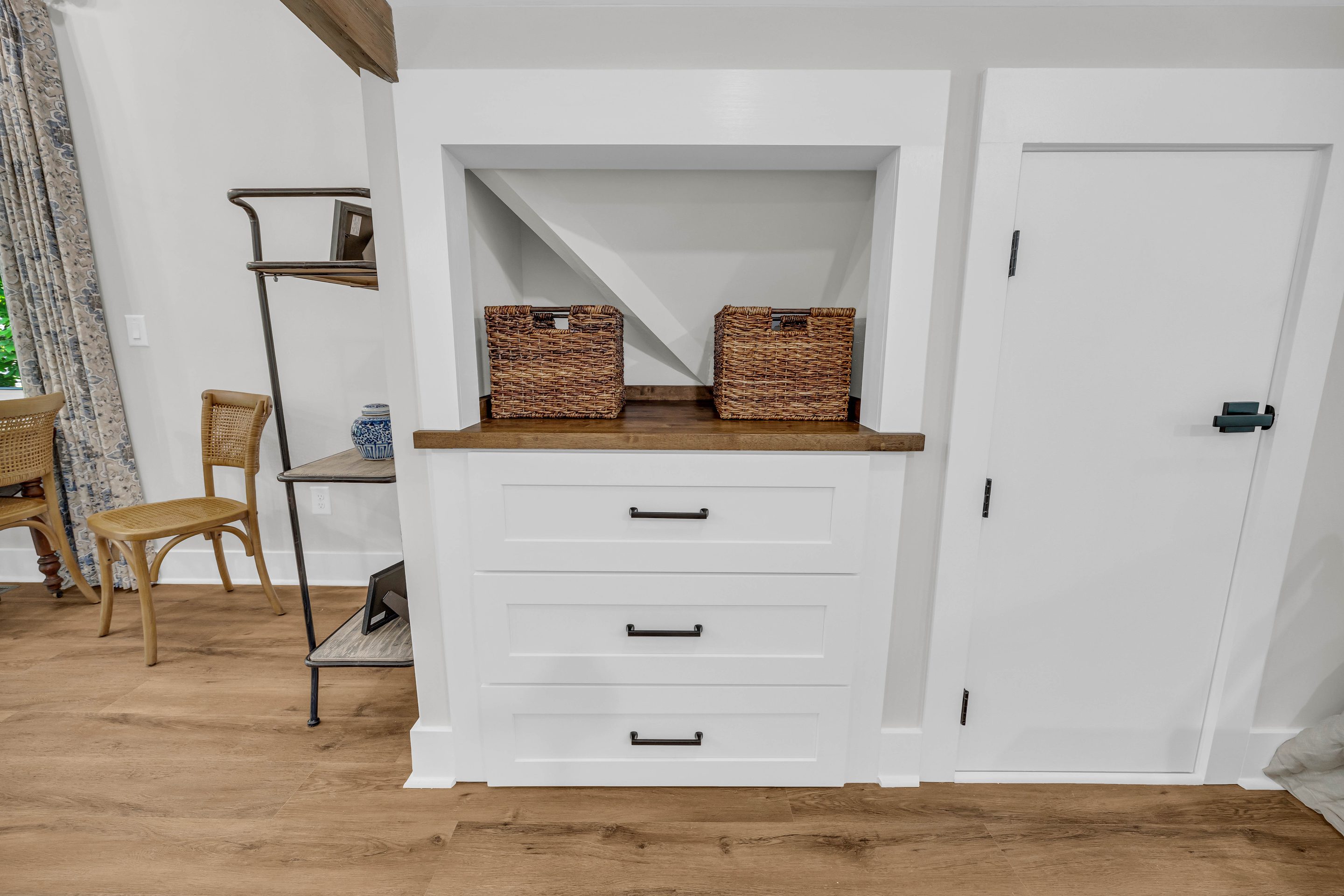 A white cabinet with baskets on top of it.