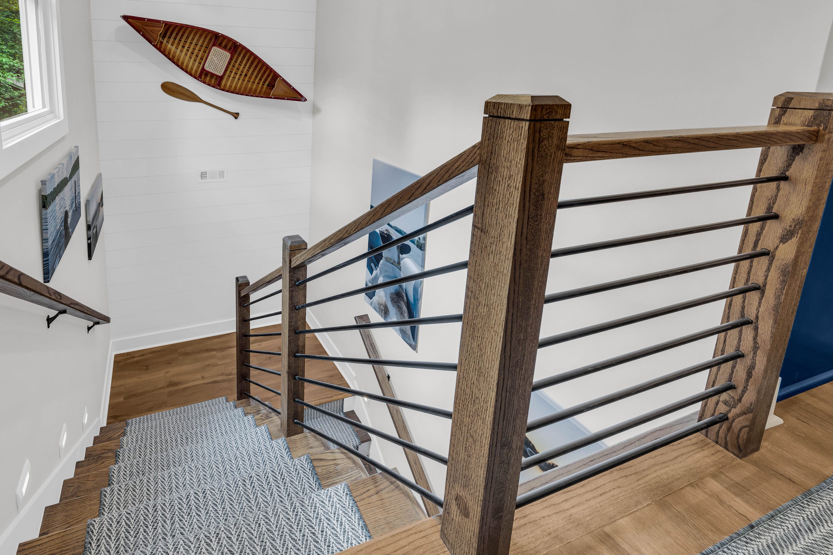 A wooden railing with metal bars on the bottom of stairs.